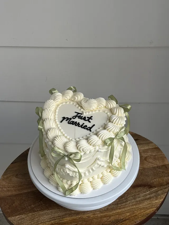 Ivory heart cake with sage green bows and "Just Married."